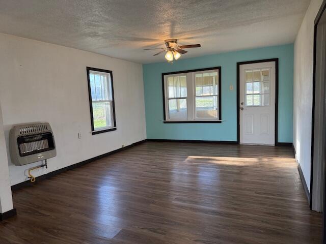 interior space featuring heating unit, a ceiling fan, wood finished floors, and a textured ceiling