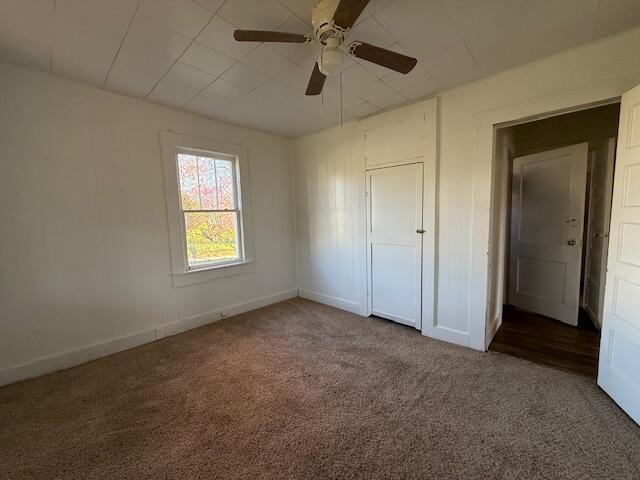 unfurnished bedroom with baseboards, a ceiling fan, and carpet
