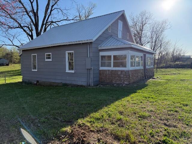 view of side of property with metal roof, a yard, and stone siding