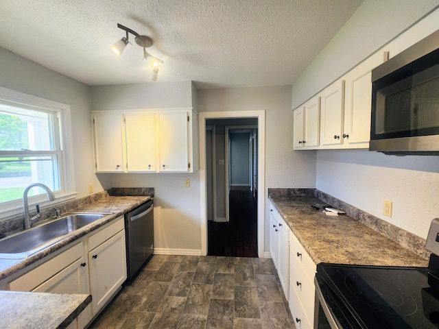 kitchen featuring white cabinetry, appliances with stainless steel finishes, a textured ceiling, and a sink