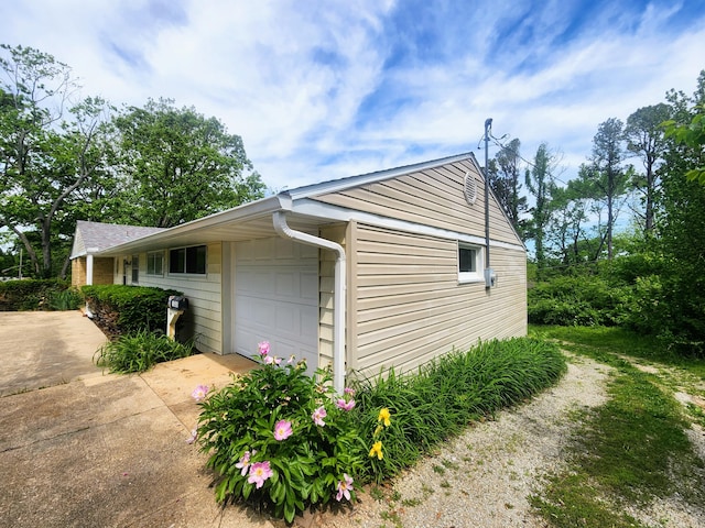 view of property exterior with an attached garage and driveway