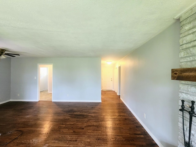 empty room with ceiling fan, a textured ceiling, baseboards, and wood finished floors