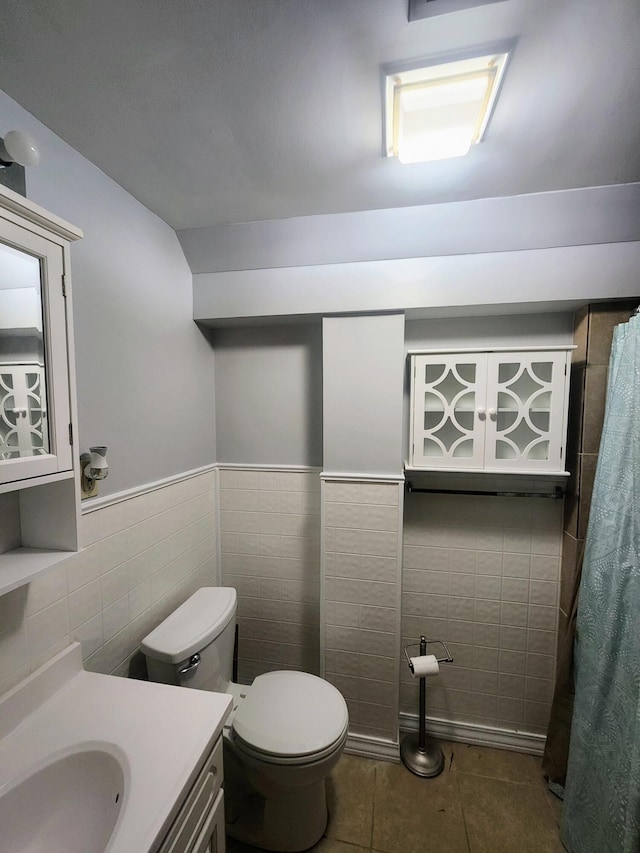 full bath with tile walls, toilet, vanity, curtained shower, and tile patterned flooring