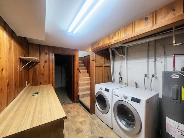 washroom with washer and dryer, laundry area, stone finish floor, water heater, and wooden walls
