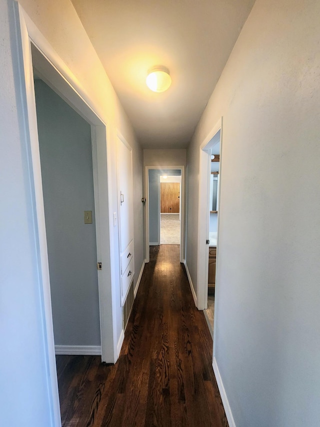 hall featuring dark wood-style flooring and baseboards