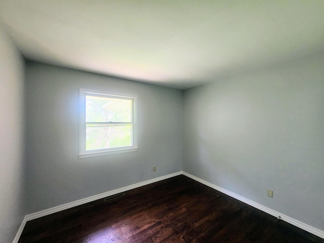 spare room with visible vents, baseboards, and dark wood-style floors