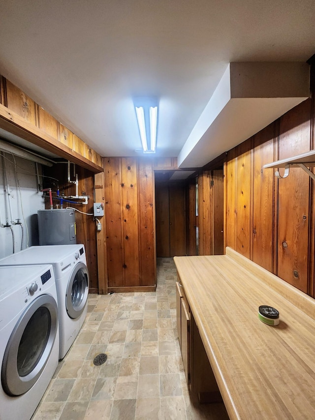 washroom featuring electric water heater, wood walls, stone finish flooring, and washer / clothes dryer