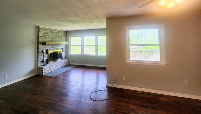 unfurnished living room with wood finished floors, a textured ceiling, a large fireplace, ceiling fan, and baseboards