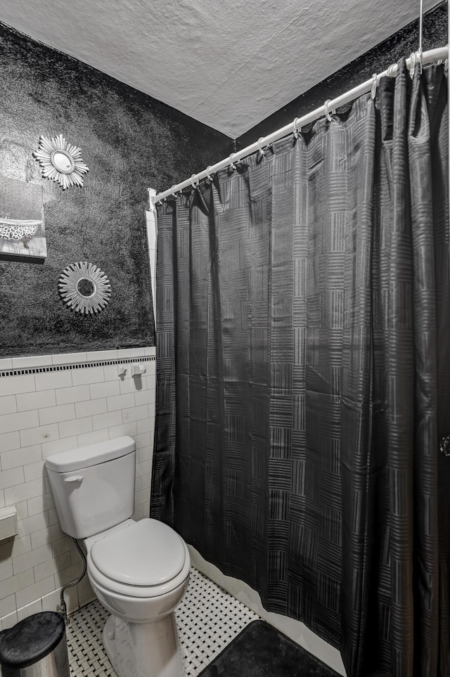 110 N Connor Ave, Joplin, MO 64801 - full bathroom with tile patterned floors, wainscoting, tile walls, toilet, and a textured ceiling