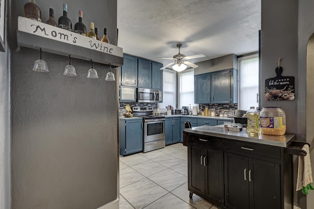 110 N Connor Ave, Joplin, MO 64801 - kitchen with ceiling fan, blue cabinetry, a textured wall, a textured ceiling, and appliances with stainless steel finishes