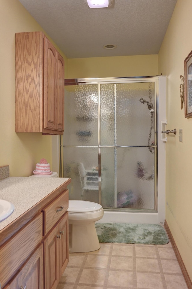 bathroom featuring toilet, a stall shower, a textured ceiling, and vanity