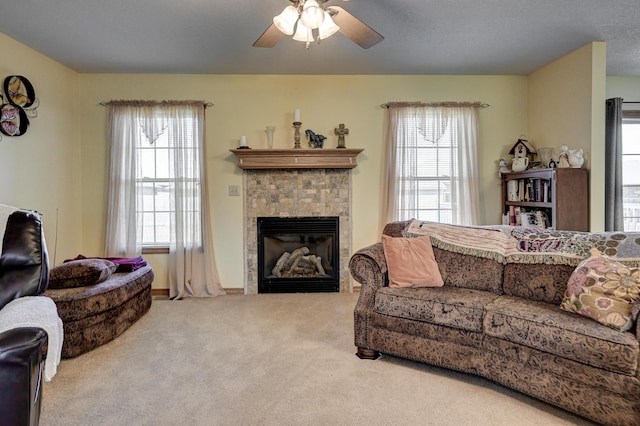 living room with a fireplace, carpet flooring, ceiling fan, and plenty of natural light