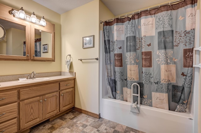 bathroom with shower / bath combo, vanity, stone finish flooring, visible vents, and baseboards