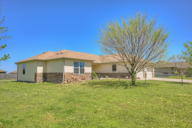 view of side of home featuring a lawn, stone siding, and fence
