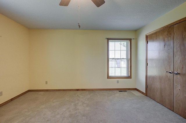 unfurnished bedroom featuring baseboards, a ceiling fan, a closet, and light colored carpet
