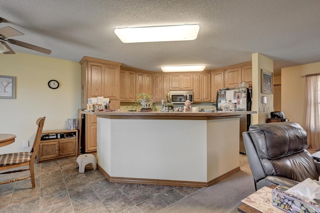 kitchen with stainless steel microwave, ceiling fan, a textured ceiling, freestanding refrigerator, and open floor plan
