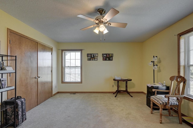 sitting room featuring baseboards, a ceiling fan, light colored carpet, and plenty of natural light