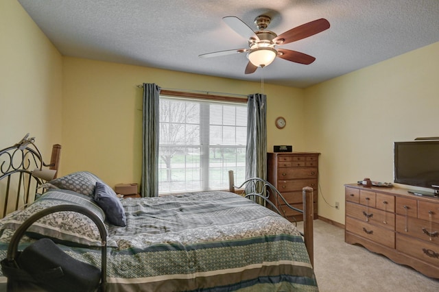 bedroom featuring a ceiling fan, light colored carpet, and a textured ceiling