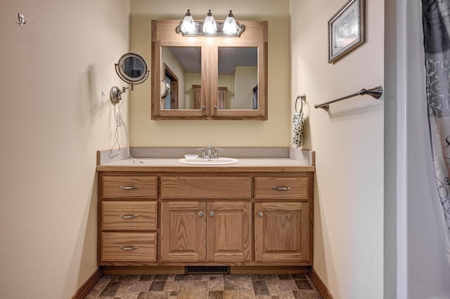 bathroom with visible vents, stone finish floor, vanity, and baseboards