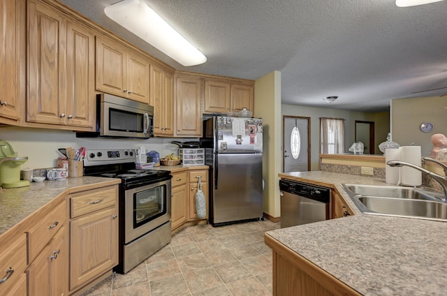 kitchen with stainless steel appliances, a textured ceiling, and a sink