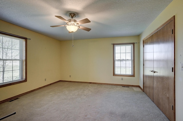 unfurnished bedroom with multiple windows, baseboards, light colored carpet, and visible vents