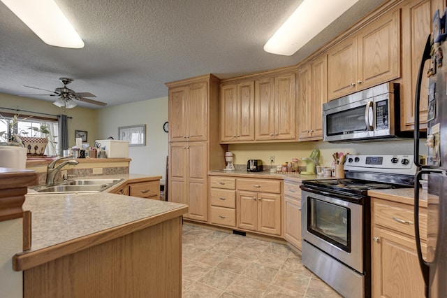 kitchen with a textured ceiling, appliances with stainless steel finishes, light countertops, and a sink
