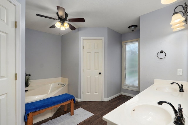 full bathroom with wood finished floors, baseboards, a garden tub, and a sink