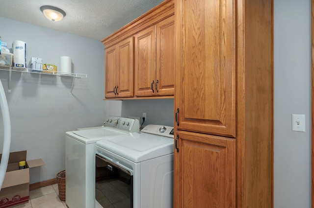 laundry area featuring light tile patterned flooring, washer and dryer, cabinet space, and a textured ceiling