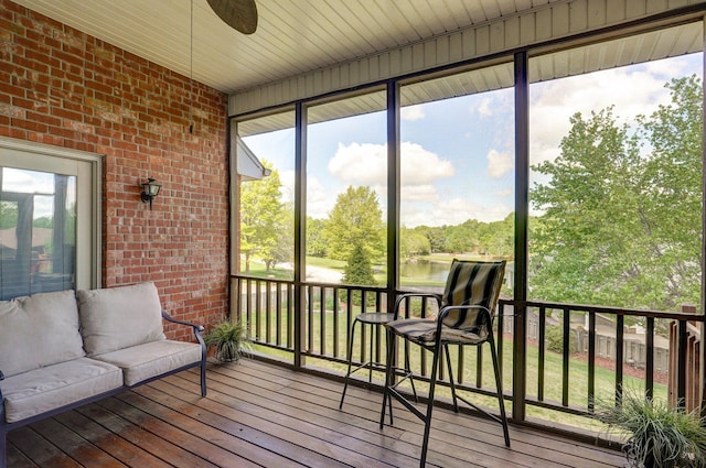 sunroom / solarium featuring a ceiling fan, a healthy amount of sunlight, and a water view
