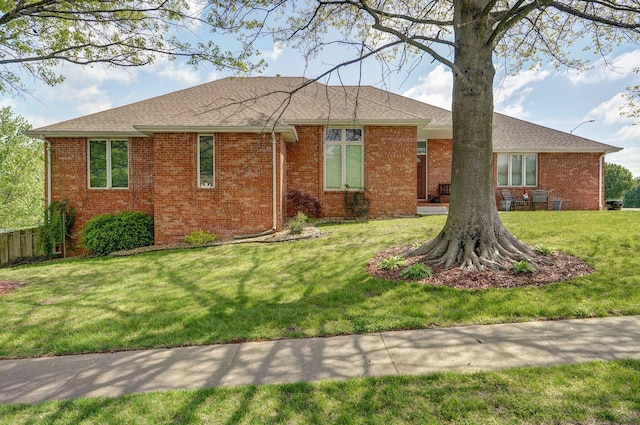 single story home with roof with shingles, a front lawn, and brick siding