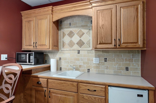 kitchen with stainless steel microwave, a sink, light countertops, refrigerator, and backsplash