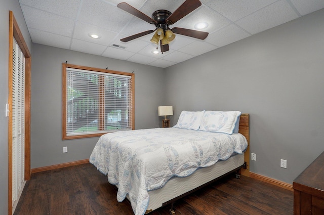 bedroom with baseboards, visible vents, wood finished floors, and a paneled ceiling
