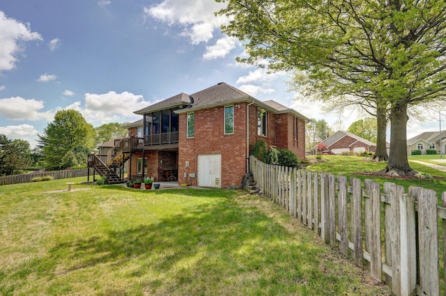 rear view of house with a sunroom, stairway, a fenced backyard, a lawn, and brick siding