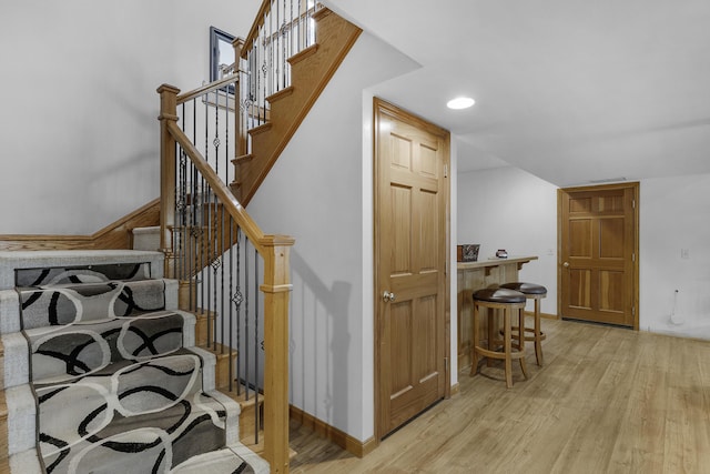 staircase with baseboards, visible vents, and wood finished floors