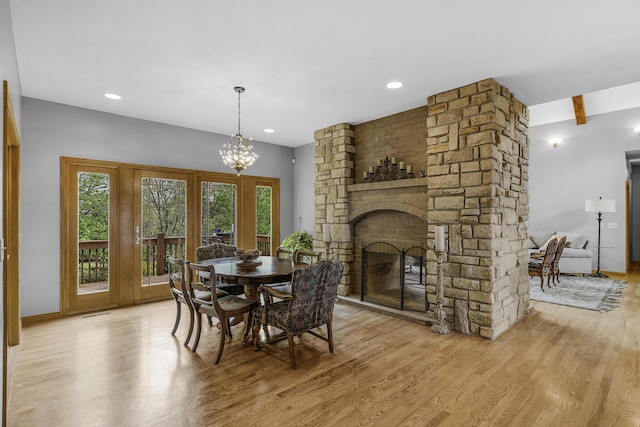 dining area with visible vents, a chandelier, baseboards, a fireplace, and wood finished floors