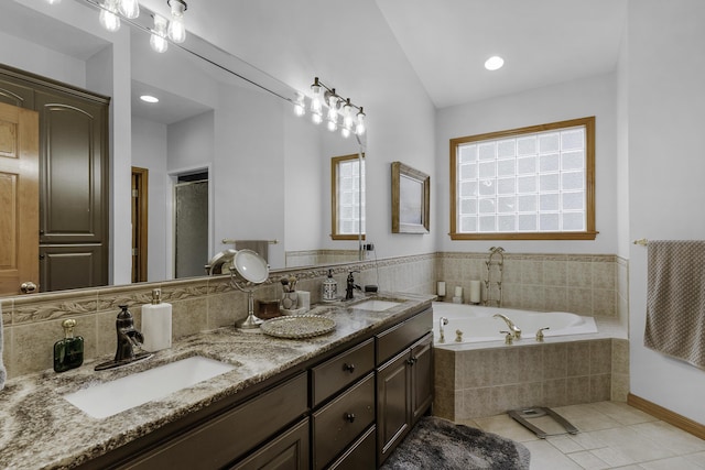 full bath with tile patterned floors, a garden tub, double vanity, and a sink