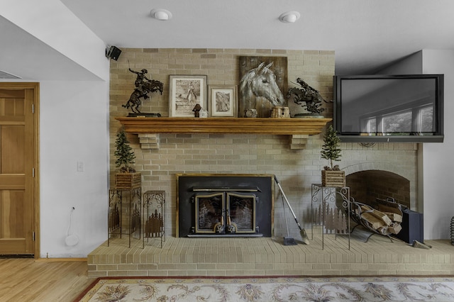 living room with wood finished floors and a brick fireplace