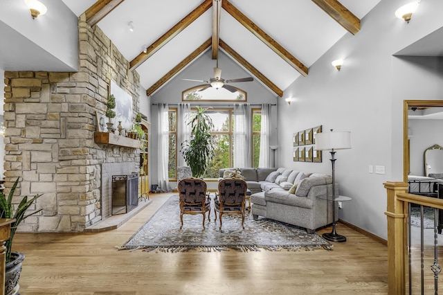 living area with light wood-style floors, high vaulted ceiling, beam ceiling, and a fireplace