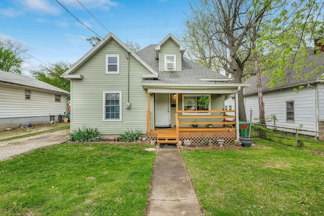 view of front of home with fence, a porch, a shingled roof, and a front yard