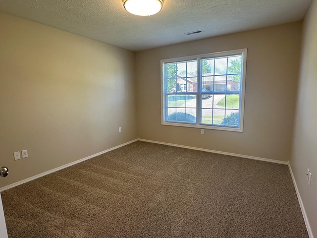 carpeted empty room featuring a textured ceiling, visible vents, and baseboards