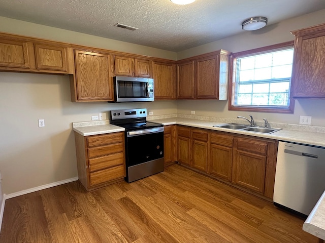 kitchen with visible vents, appliances with stainless steel finishes, brown cabinetry, and a sink