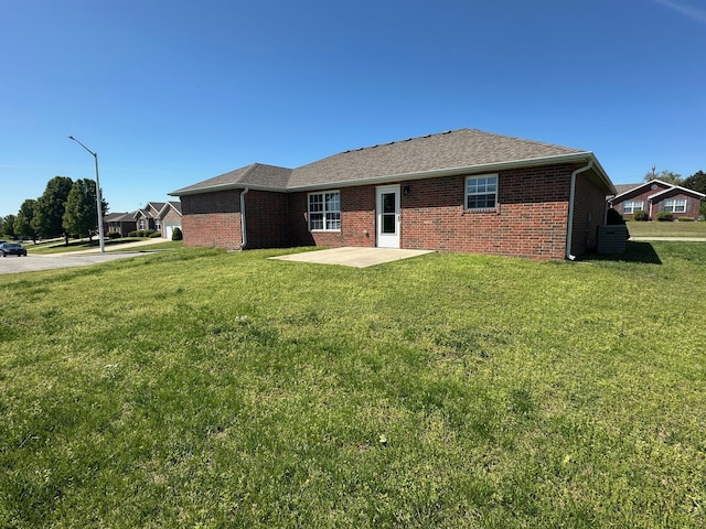 rear view of property featuring brick siding, a yard, and a patio area