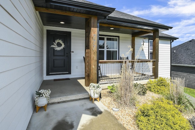 doorway to property featuring a porch and a shingled roof