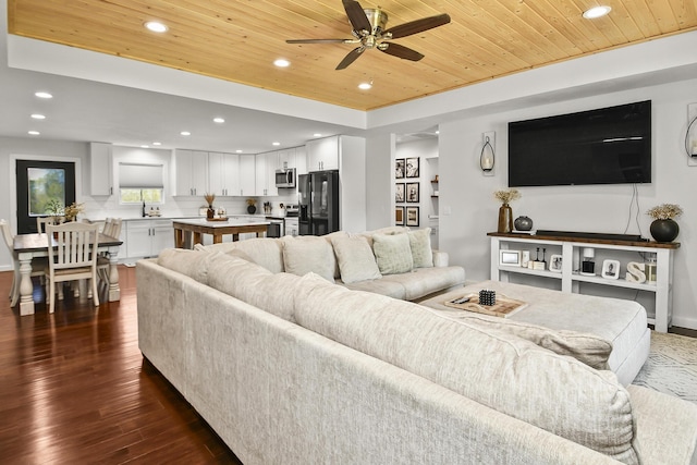 living area featuring dark wood-style floors, recessed lighting, ceiling fan, a tray ceiling, and wood ceiling