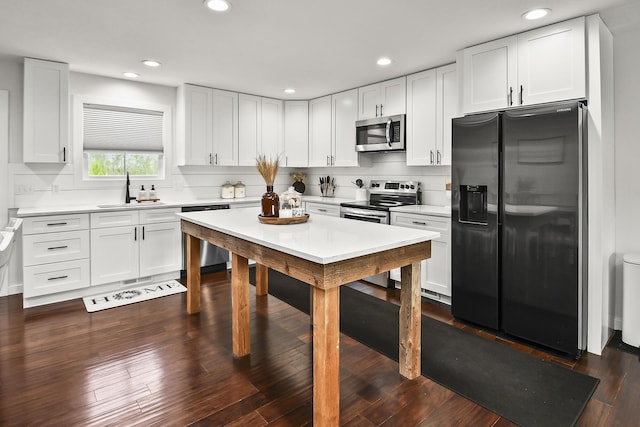 kitchen with white cabinetry, stainless steel appliances, light countertops, and a sink