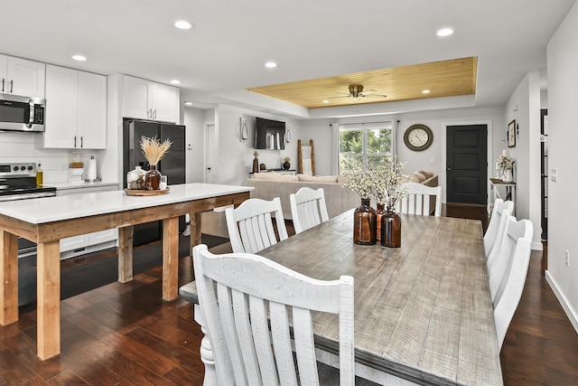 dining room with recessed lighting, a tray ceiling, and dark wood-style floors