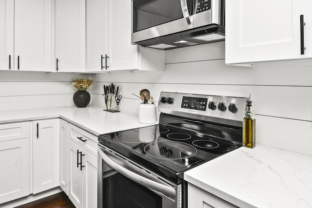 kitchen featuring appliances with stainless steel finishes, white cabinetry, and light stone countertops