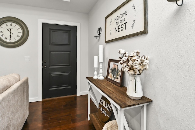 foyer with dark wood-style flooring and baseboards