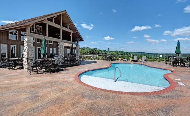 community pool with a patio, outdoor dining space, and fence