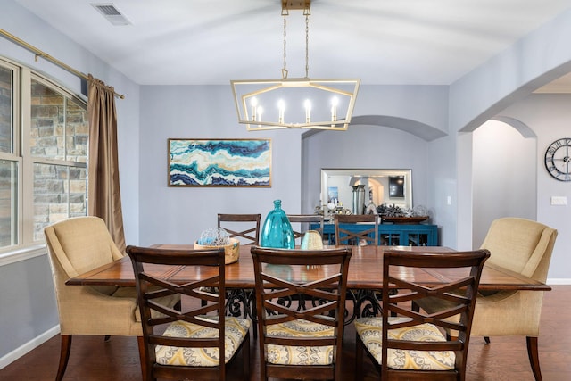 dining space with an inviting chandelier, visible vents, baseboards, arched walkways, and wood finished floors
